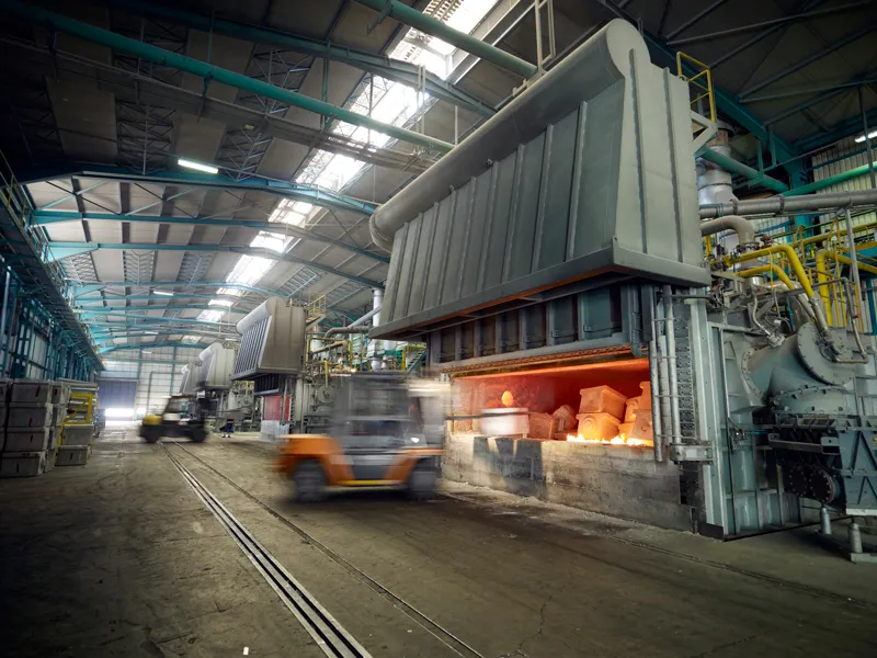 Large industrial furnace glowing with heat inside a steel-framed manufacturing plant